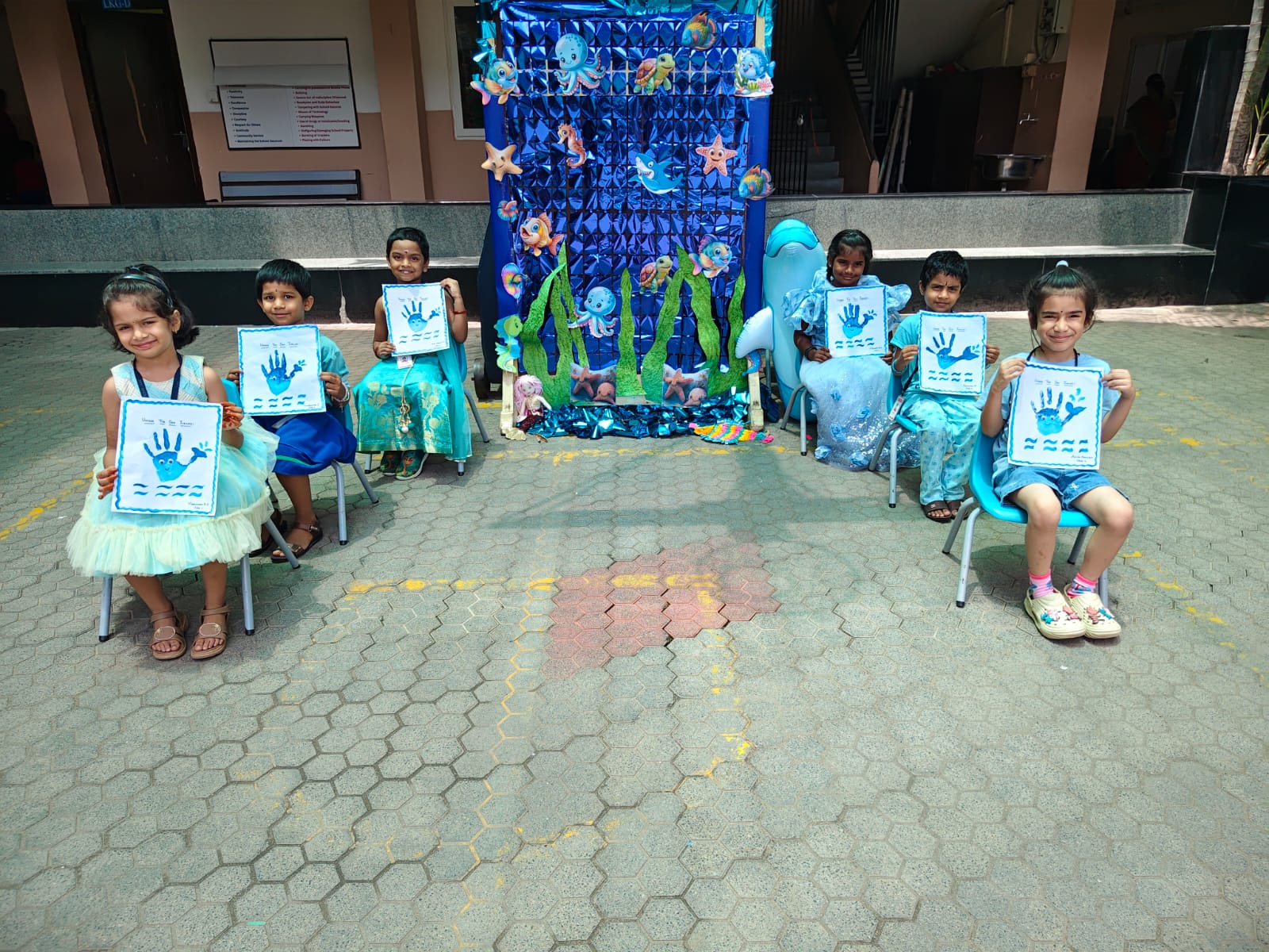 Kindergarten students with Save the Sea Creatures handprint crafts on Deep Blue Craft Day