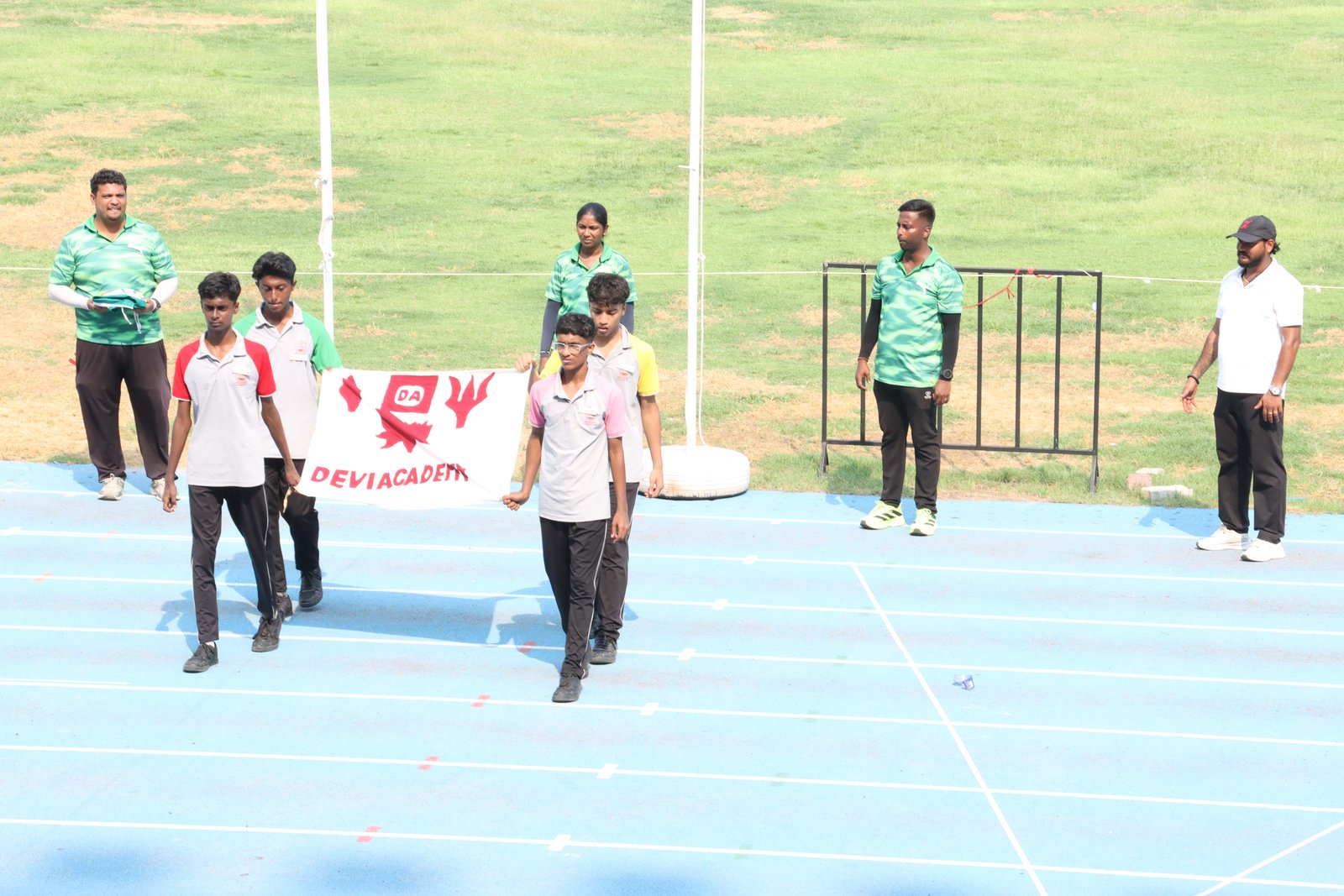 Students carry the school flag on the stadium track
